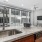 Kitchen peninsula open to living space with floor-to-ceiling windows